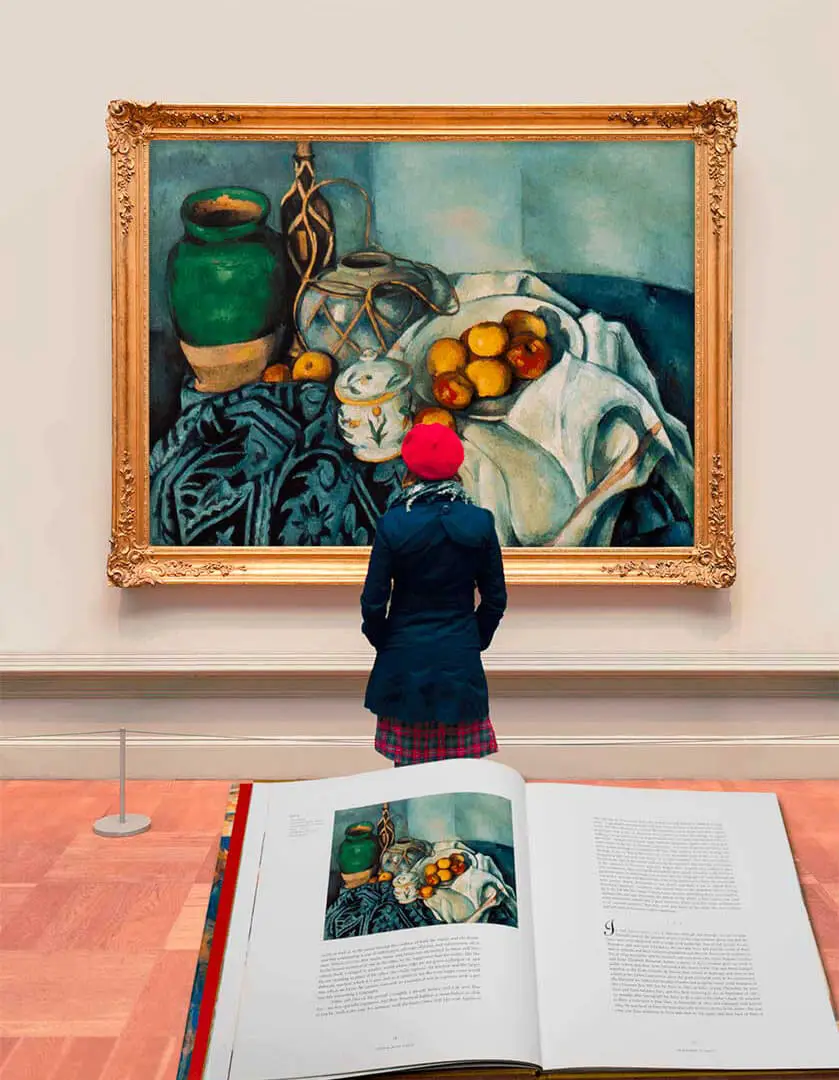 Visitor viewing a Cézanne still life above an open art book
